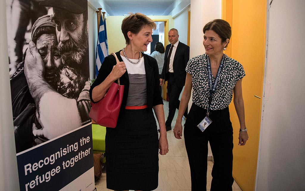 Bundesrätin Simonetta Sommaruga mit der Direktorin der griechischen Asylbehörde, Maria Stavropoulou. Links ist ein Plakat mit einem Foto von Flüchtlingen und der Aufschrift 