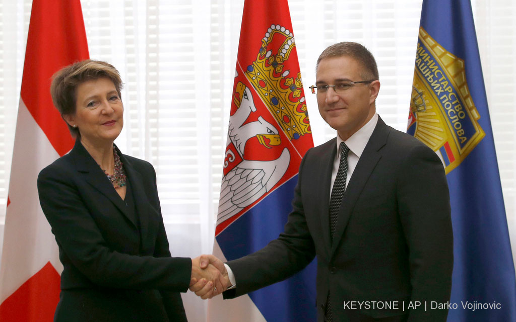 Le ministre serbe de l’intérieur Nebojša Stefanović (à droite) salue la conseillère fédérale Simonetta Sommaruga. À l’arrière-plan, les drapeaux de la Suisse et de la Serbie.