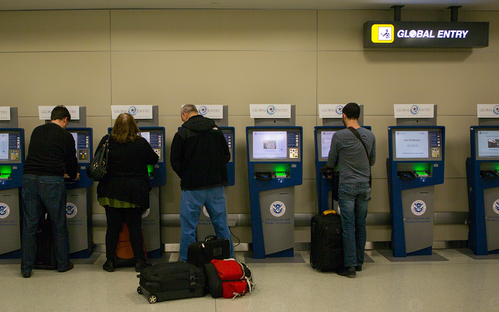Travelers standing at Global Entry Kiosks at an international airport