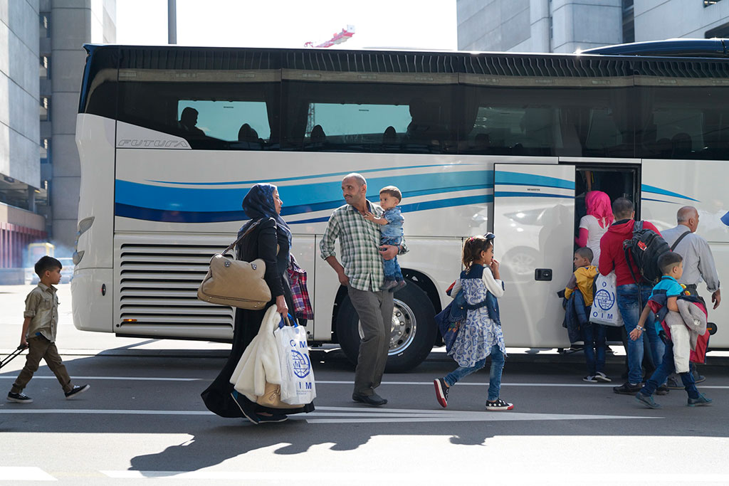 A Syrian family with three children get on a bus at Zurich airport along with other resettlement refugees.